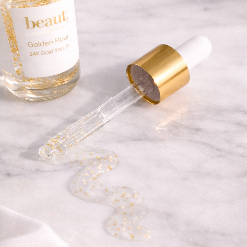 Close-up of Golden Hour 24K Gold Serum dropper and serum texture on marble