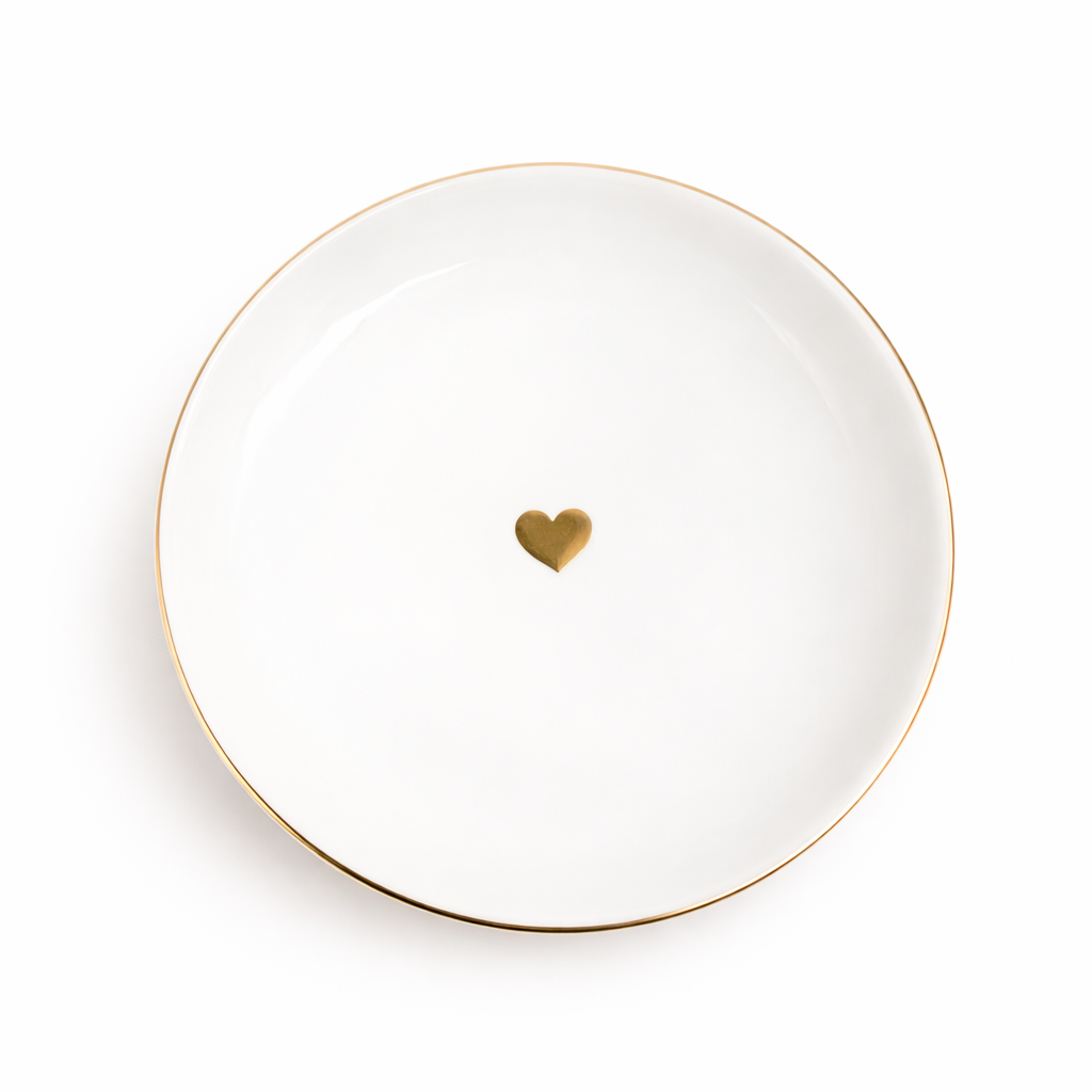 Minimal white jewelry dish with a small gold heart detail and delicate gold rim, shown from above on a clean light background